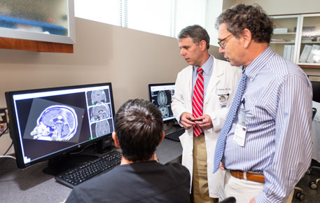 Gamma knife providers reviewing data on a computer screen.