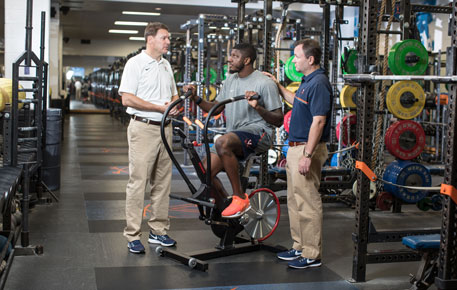 Athlete and doctors in weight room