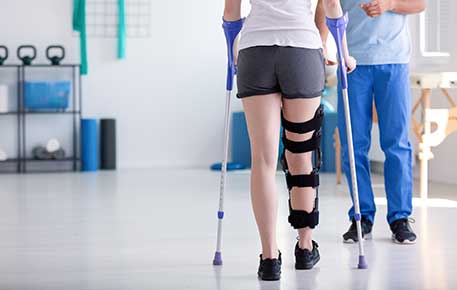 A woman learning to walk with crutches after traumatic injury getting UVA  rehab services