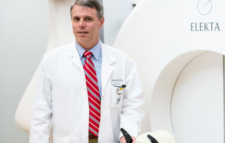 A gamma knife provider standing in front of the gamma knife machine.