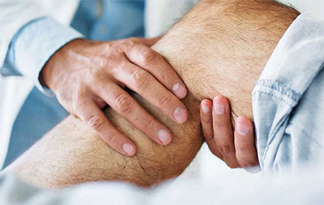 A provider using their hands to check a patient's knee.