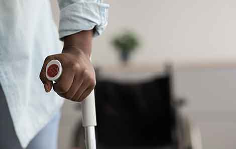 A black person holding the handle of a crutch.