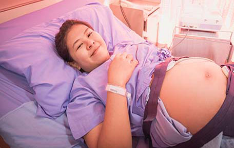A pregnant woman smiling in a clinic bed