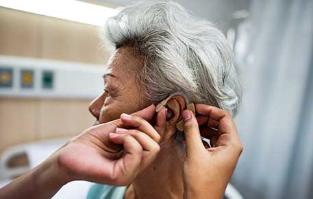A woman is fitted for a hearing aid.
