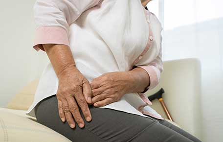A woman touches her hip, where the hip replacement needs fixing