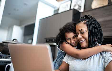 Mother and daughter hugging while making a mammogram appointment online