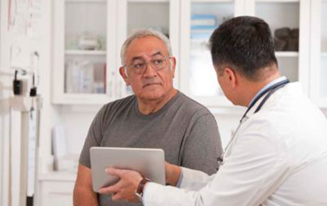 A man looking at a provider who is showing the man a tablet screen.