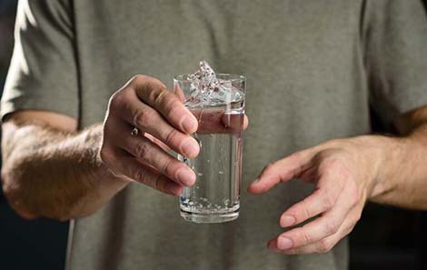 person holding glass of water with shaky hands